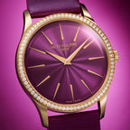 Luxury Patek Philippe watch with purple face and gold accents on a pink background