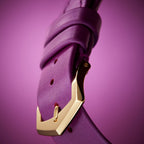 Close-up of a purple strap with a gold buckle on a purple background