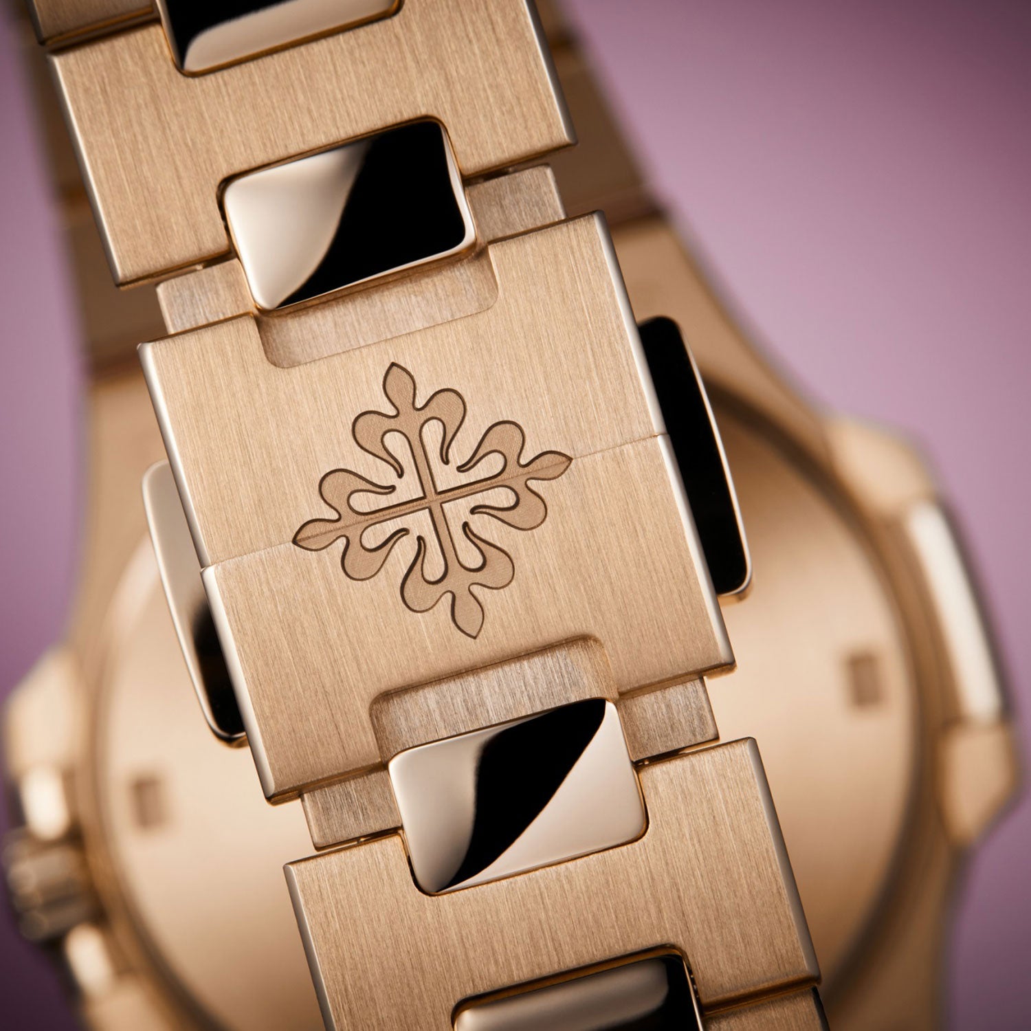 Close-up of a gold watch with a decorative emblem on a purple background